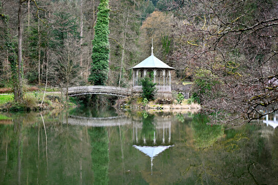 Small island with old pavilion and bridge in the forest lake