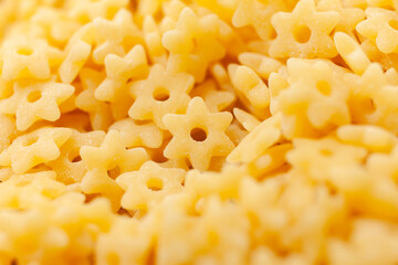 Uncooked yellow small stars shaped pasta background. Top view. Close-up