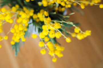 A spring bouquet of flowers with yellow mimosa flowers in the home interior. International Women's Day or birthday.