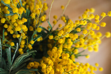 A spring bouquet of flowers with yellow mimosa flowers in the home interior. International Women's Day or birthday.