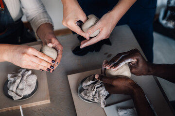 Cropped picture of hands modeling clay at pottery masterclass.