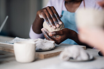 Cropped picture of interracial craftswoman's hands making earthenware