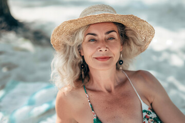 55 year old woman with swimsuit and pamela hat on the beach