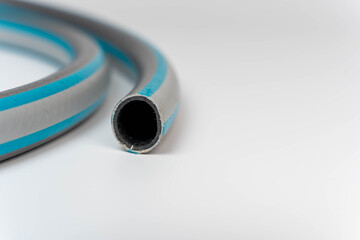 Flexible pvc garden hose coiled on white background with copy space