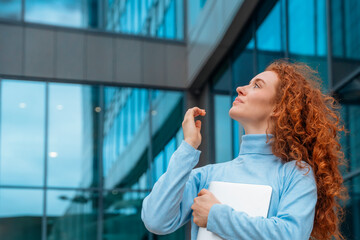 a young redhead fun and huppy  woman  in white shirt talking and using on her mobile phone, using mobile in an urban modern city. Lifestyle photos