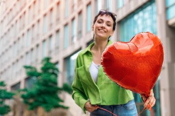 happy woman with a heart-shaped balloon falling a love, having a fun day, walking around  a city...