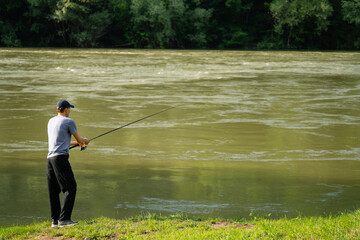 Man fishing on the mountain river at evening