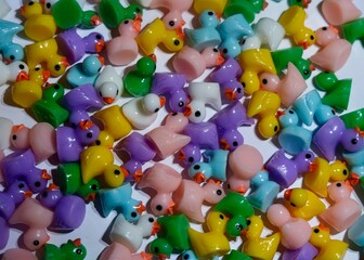 Miniature plastic ducks in lots of colours scattered around, filling the whole picture
