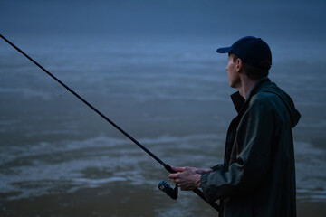 Man fishing on the mountain river at evening