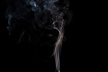 incense stick with yellow  smoke against black background