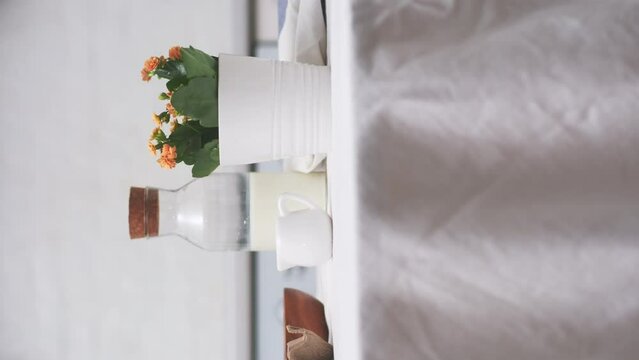 Easter celebration concept. Easter eggs, bottle of milk, flowers in white pot on white table in light kitchen.