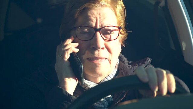 Elderly woman committing a traffic violation, talking on the phone driving a car.