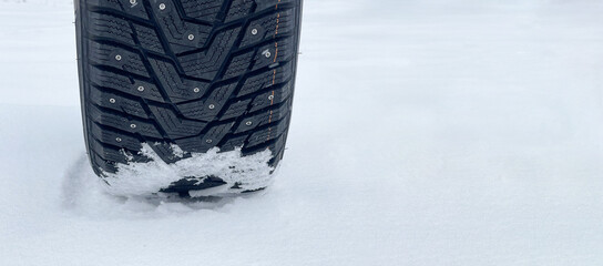 Winter tire with spikes in the snow with text space
