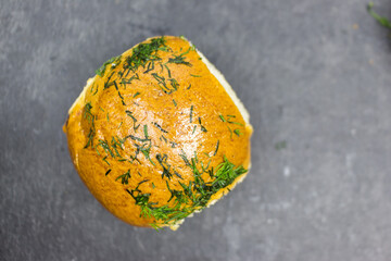 One rich, fluffy fresh bun with garlic and dillon a black kitchen board. Top view