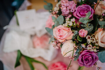 Valmiera, Latvia - March 7, 2024 - A vibrant bouquet of roses and mixed flowers, focus on a deep purple rose surrounded by pink roses, greenery, and small white blooms, with a blurred background...