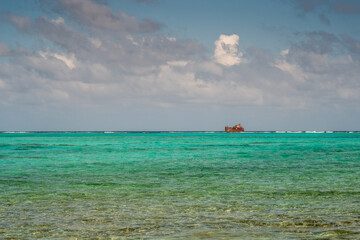 The turquoise sea of the reef with a shipwreck on the horizon line. San Andrés island, Colombia.