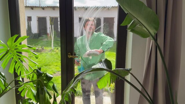 man wipes window at home with tissue and  leaner spray