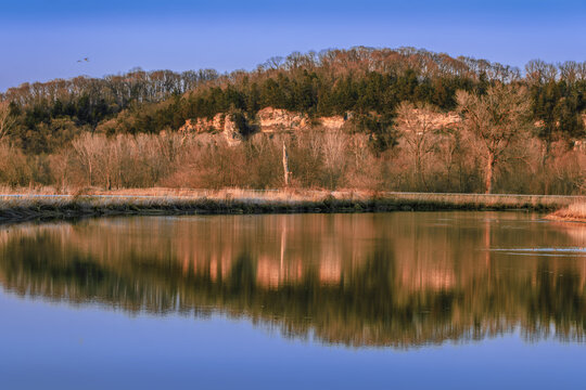 View of Missouri River bluffs  reflecting in calm water at sunsets early in spring; clear sky in background