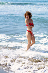 Happy female smiling while standing in wavy sea