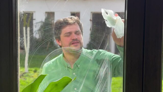 man wipes window at home with tissue and  leaner spray