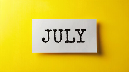 JULY written on a white sheet of paper on a yellow background