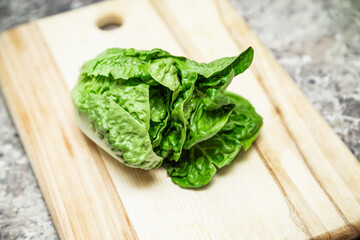 Cabbage baby cos lettuce on wooden cutting board. Healthy  grocery. Romaine lettuce heads. Asian vegetables ready to cook.