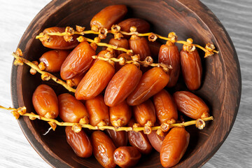 Sweet dried dates on a branch in wooden kitchen bowl. Oriental treats. Healthy nutritious snack