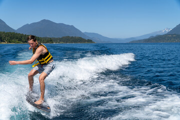 Young man enjoying wake surfing on the lake on a beautiful summer day in southern Chile.