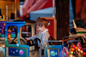 A smiling toddler enjoys a whimsical carousel ride, his expression one of sheer delight amidst the...