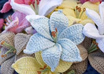 Close up on bouquet of beautiful hand crafted crochet flowers. blue, yellow, pink poinsettia style flowers.