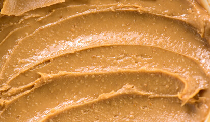 Peanut butter texture swirls background. Creamy smooth peanut butter backdrop, organic food. American cuisine. Top view