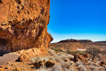 Eroded red laterite rock face and distant butte in the outback near Mount Magnet, mid-west of...