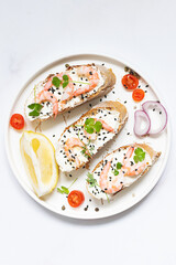 Bruschette set with shrimps, cream cheese and lemon on white marble plate top view.