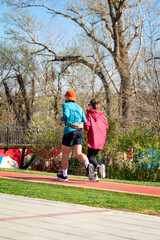 Young fit couple running together on red outdoor track 