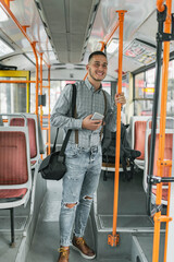 Fototapeta na wymiar Handsome Young Adult Standing in the Public Bus and Using His Mobile Phone