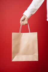 Minimalist Shopping Concept: Hand Holding Paper Bag on Red Background
