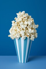 Classic Movie Snack: Overflowing Popcorn in Striped Box on Blue Background
