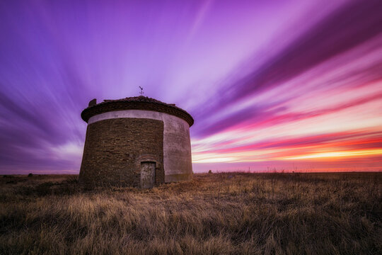 Sunset with intensely colored clouds over the Ledigos dovecote, Tierra de Campos, Palencia in summer with dry grass around