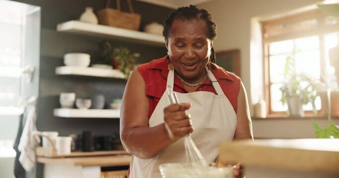 Elderly, woman and happiness for baking in kitchen with whisk, bowl and apron for cake, cookies and talking. Senior, african person and smile for cooking, chef and retirement fun with mixing in home