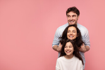 Happy family, mother father and daughter posing, embracing while standing in line, looking together...