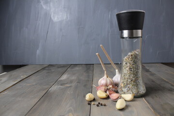 A salt shaker with seasoning and salt garlic lies next to it on a gray background with space for text. Selection of seasoning for dishes