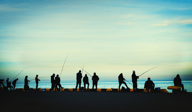 fishermen fishing on harbour at dusk