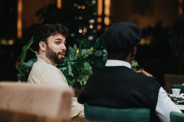 Male multiethnic business associates engaging in a casual meeting in a cozy restaurant setting with coffee cups and a festive backdrop.