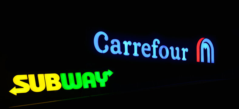 Hypermarket Carrefour and SubWay fastfood, neon signages on facade at night