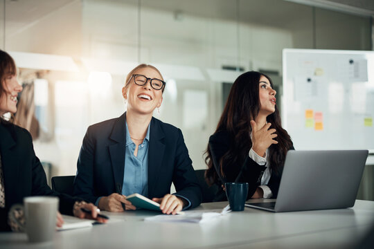 Laughing group of diverse businesswomen talking during an office meeting together