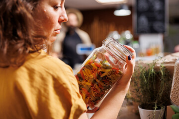 Environmentally conscious customer in zero waste bulk products shop looking for homemade pasta. Client purchasing organic non GMO food in eco friendly local neighborhood supermarket
