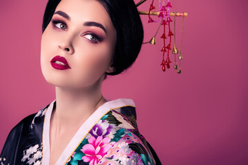 Portrait of stunning chinese girl performing kabuki art with traditional make up on pink gradient...
