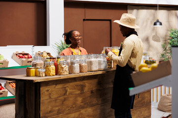 Male shop owner discussing fresh fruits and vegetables at local market with a smiling black woman....