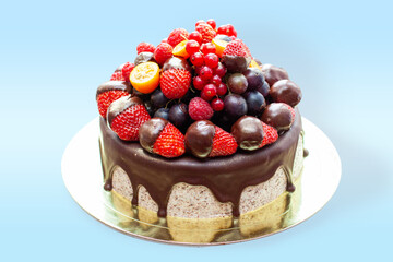 Cake decorated with strawberry dipped into melted chocolate, raspberry, blueberry and red currant. Isolated on plain background