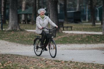 Mature woman cycling through a tranquil park, enjoying a leisurely ride outdoors.